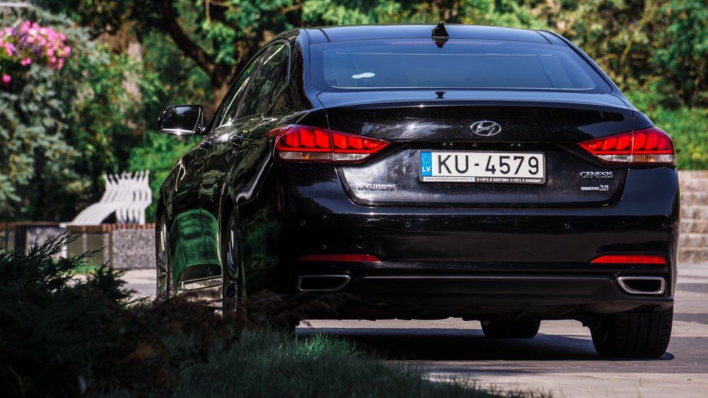 Ceļa malā stāv melns hyundai genesis.