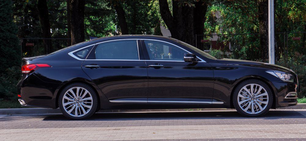 Ceļa malā stāv melna mašīna.