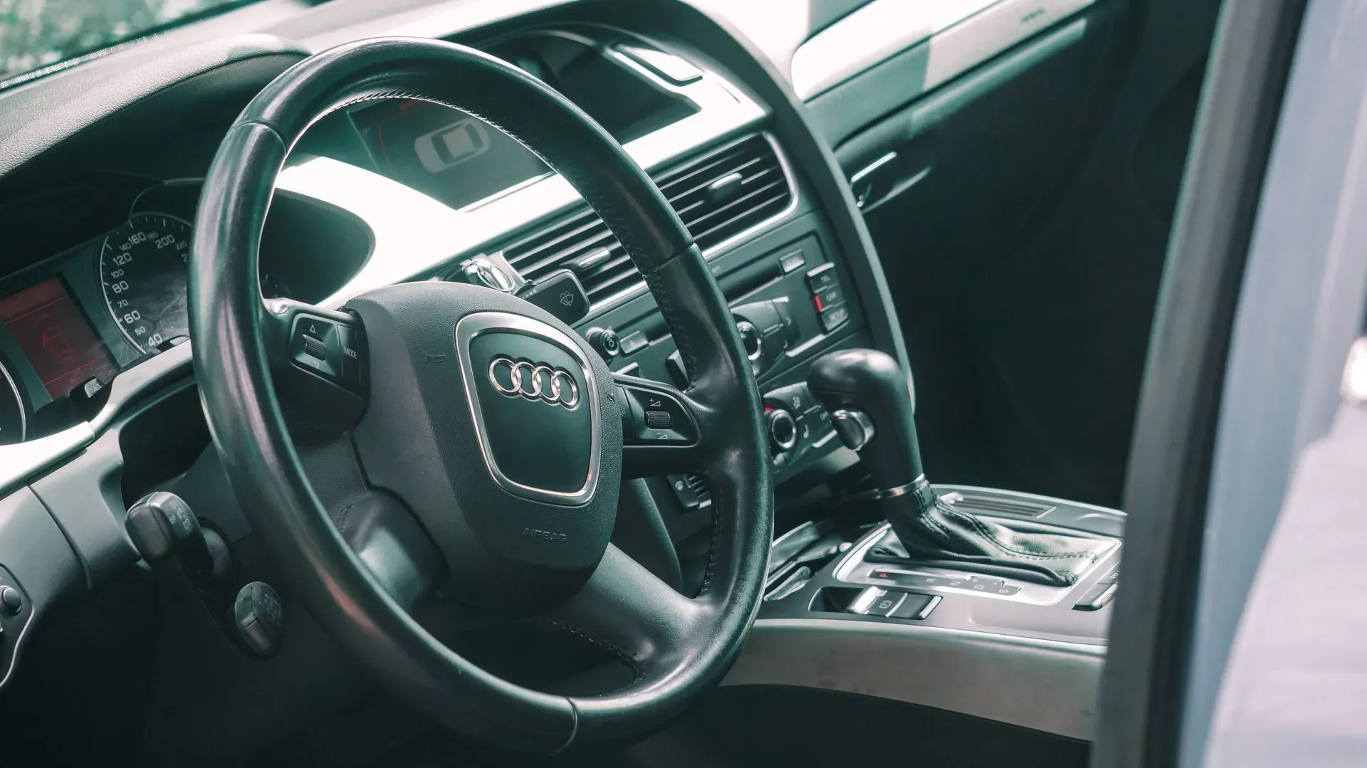 Tuvplāns no stūres automašīnā ar atvērtām durvīm.