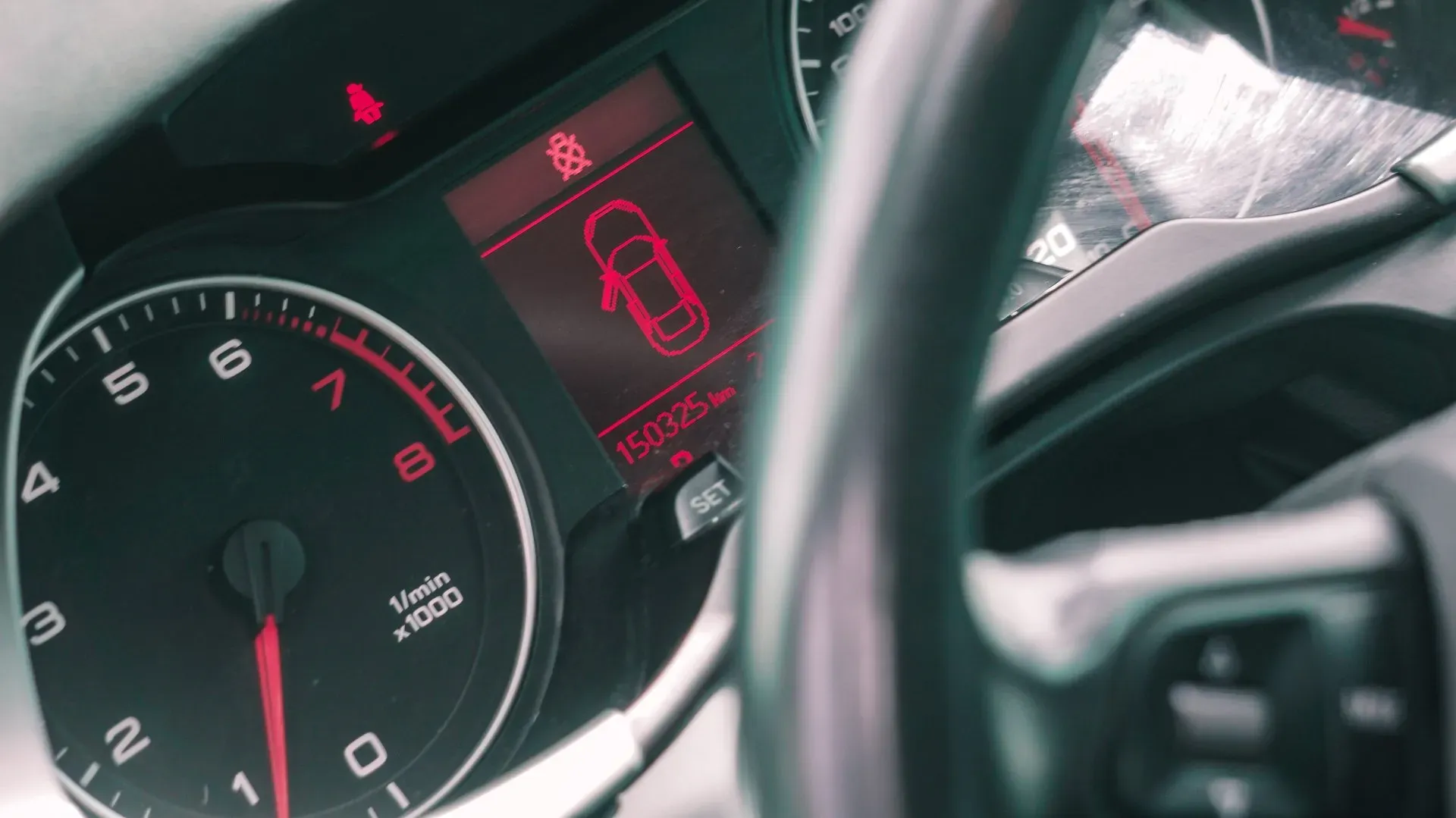 Tuvplāns no automašīnas paneļa ar sarkanu automašīnu uz ekrāna.