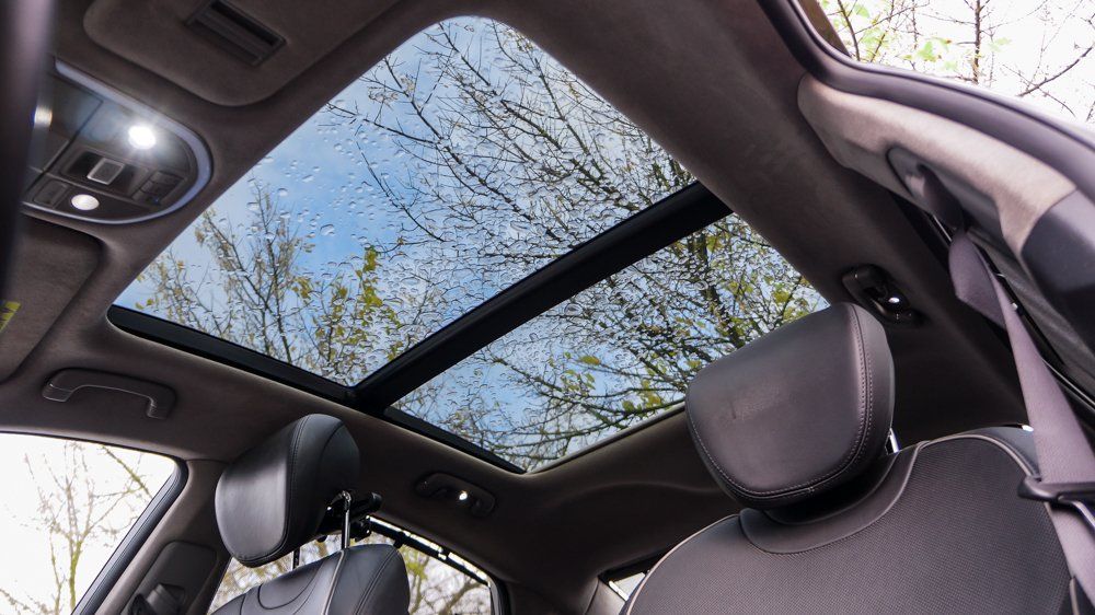 Auto ar jumta lūku un kokiem fonā.