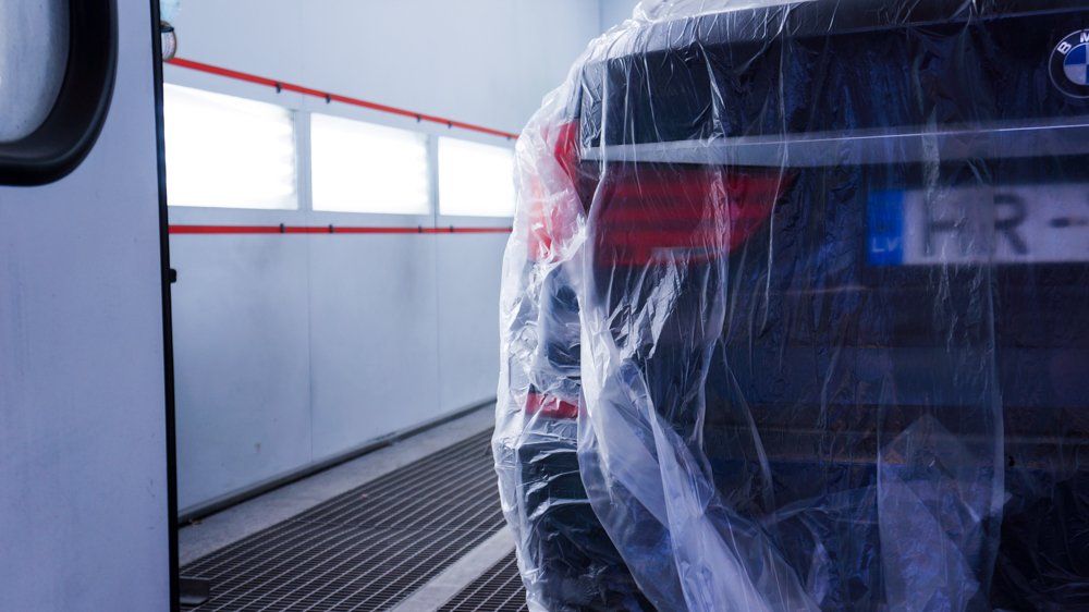 Auto ir ietīts plastmasā krāsošanas kabīnē.