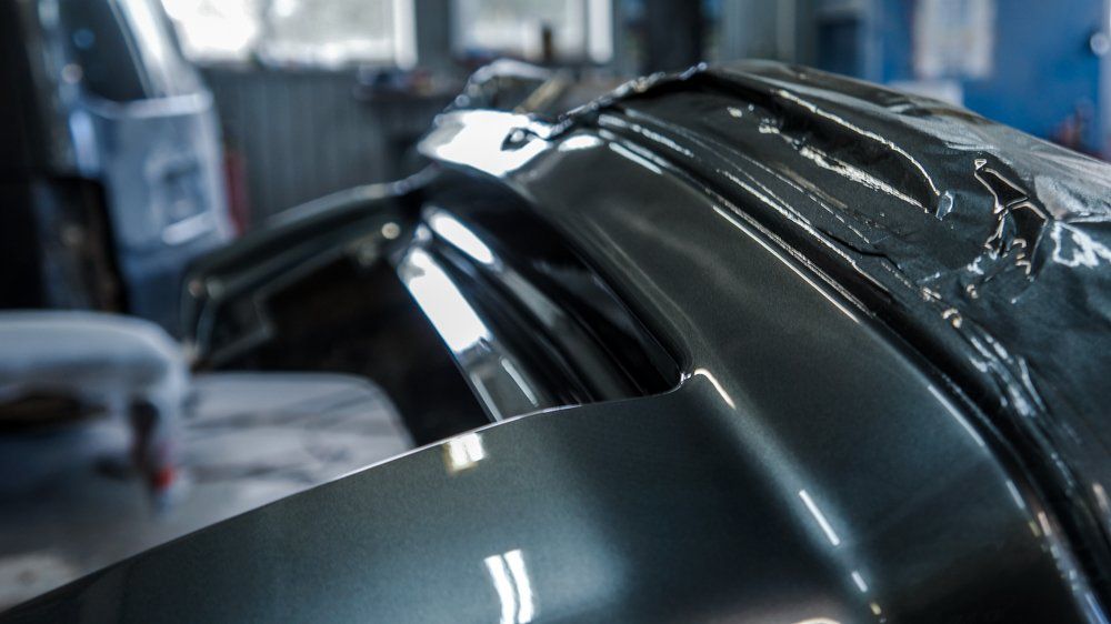 Tuvplāns ar plastmasā ietītu automašīnas riteni garāžā.