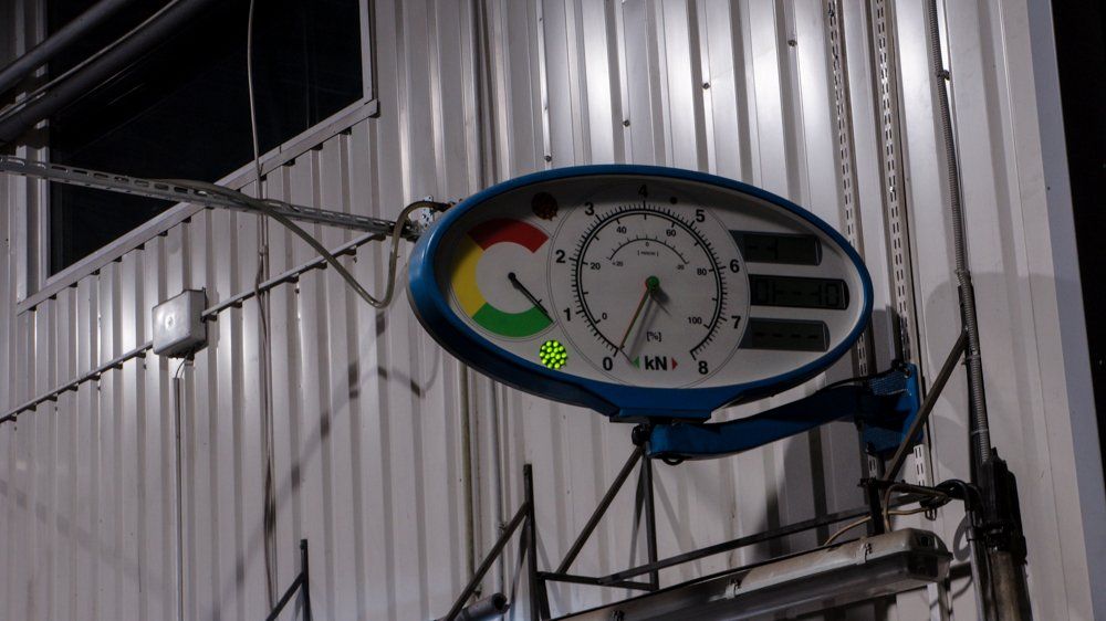 No ēkas sāniem karājās pulkstenis.