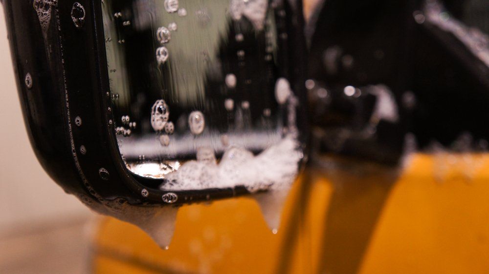 Tuvplāns automašīnas sānu spogulis ar ūdens pilieniem uz tā.