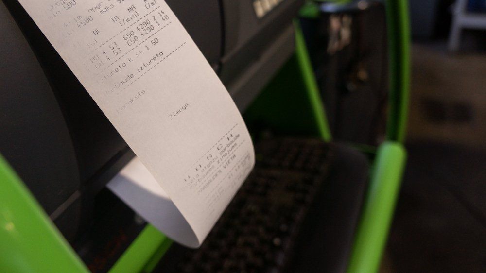 Uz zaļa printera tiek drukāta kvīts