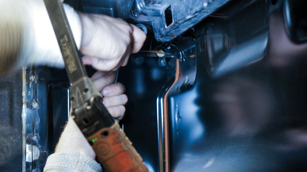 Cilvēks ar zāģi griež metāla gabalu.