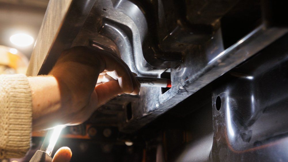 Cilvēks strādā pie mašīnas ar uzgriežņu atslēgu.