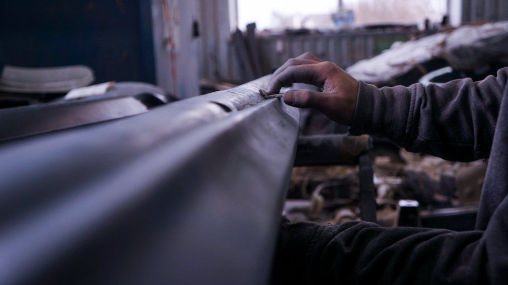 Cilvēks strādā pie metāla gabala darbnīcā.