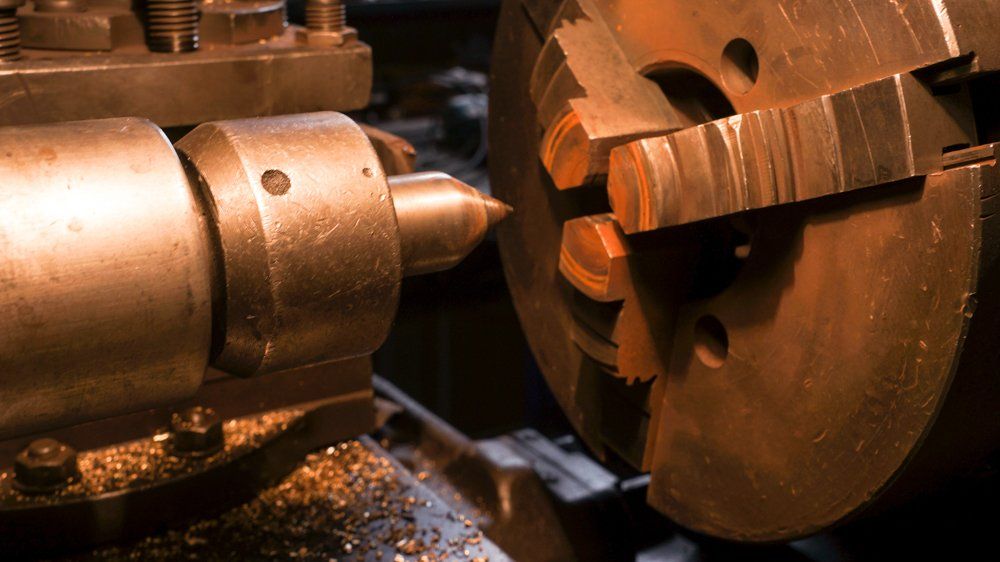 Mašīna griež metāla gabalu uz virpas.