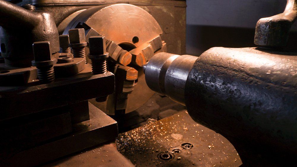 Mašīna griež metāla gabalu uz virpas.