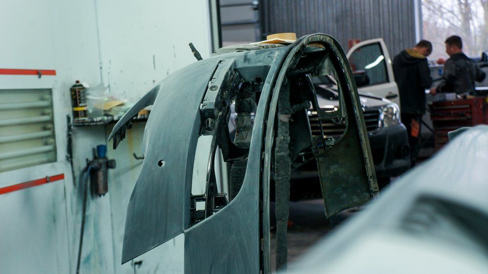 Vīrietis garāžā strādā pie mašīnas.