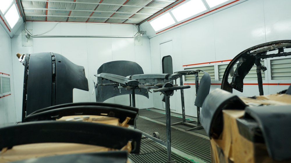 Krāsošanas kabīnē tiek krāsota automašīna.