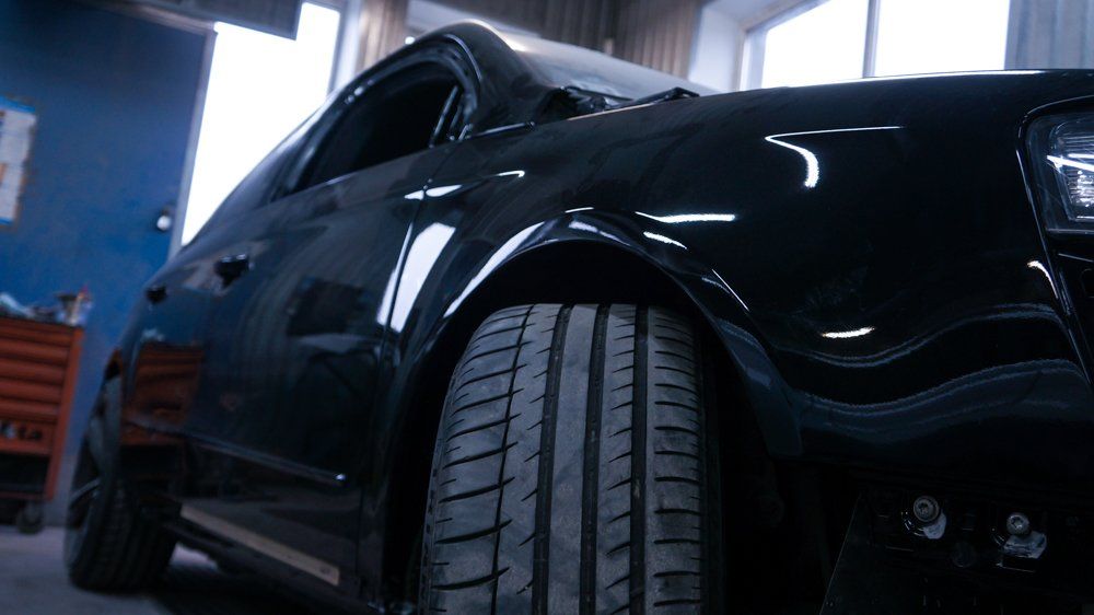 Tuvplāns melnai automašīnai ar riepu garāžā.