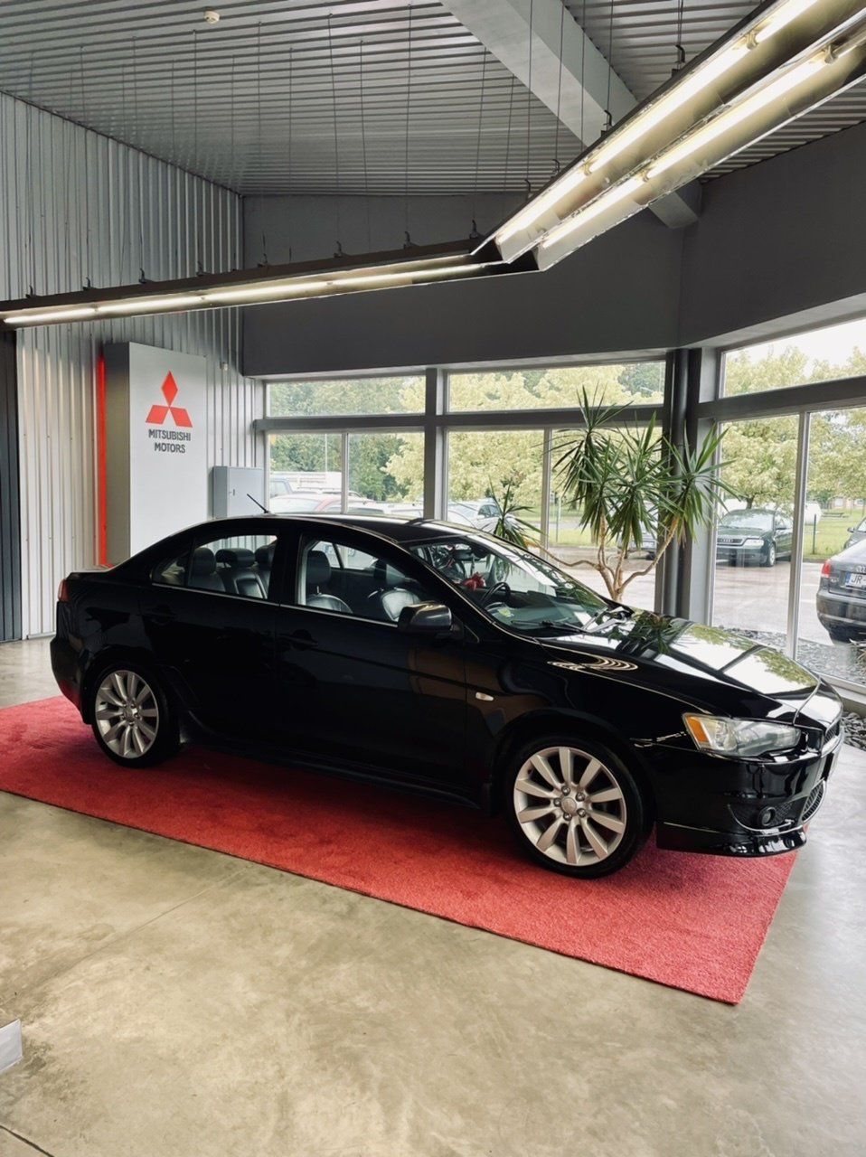 Melna automašīna ir novietota uz sarkana paklājiņa salonā.