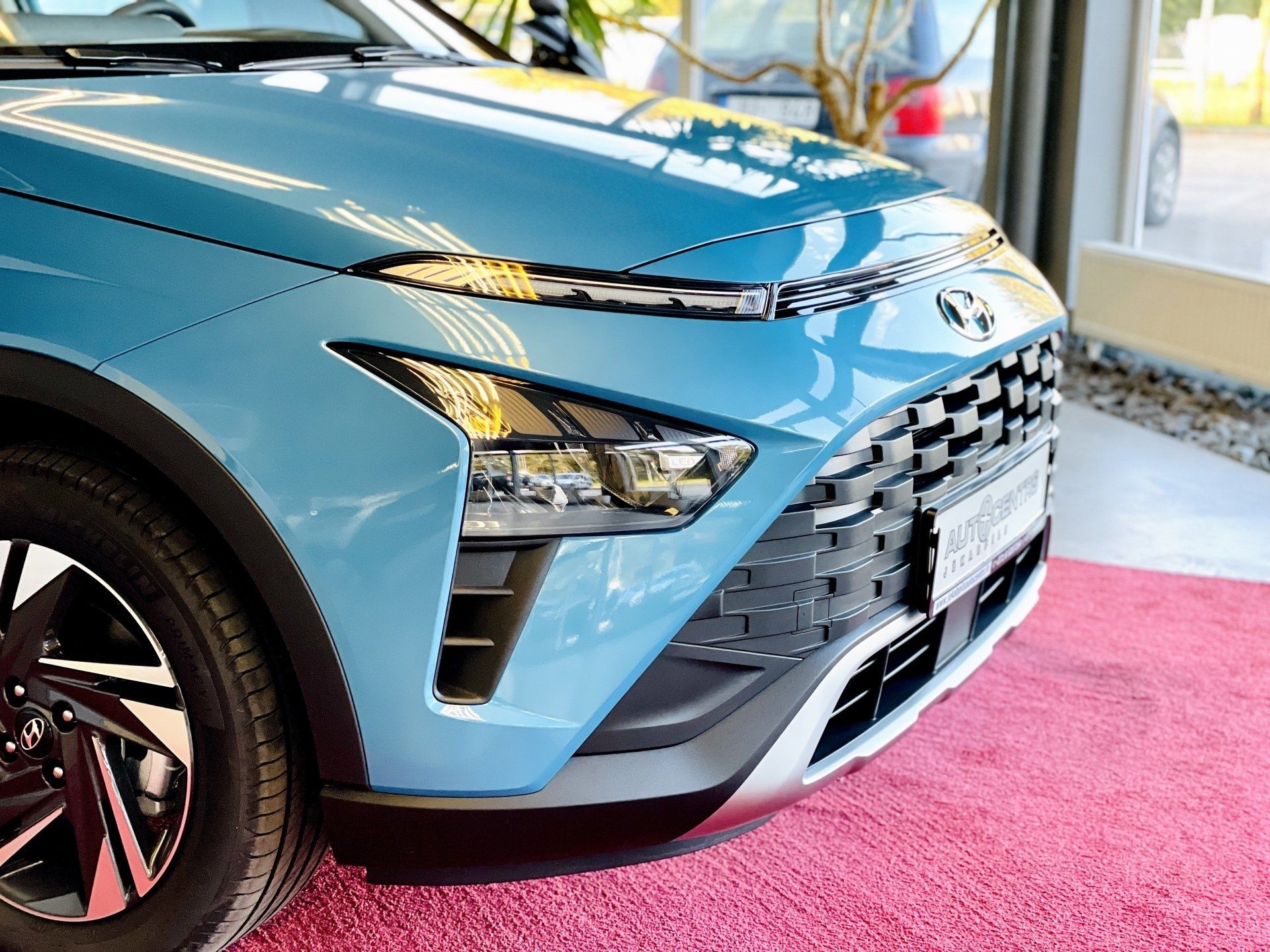 Zila mašīna ir novietota uz rozā paklāja salonā.