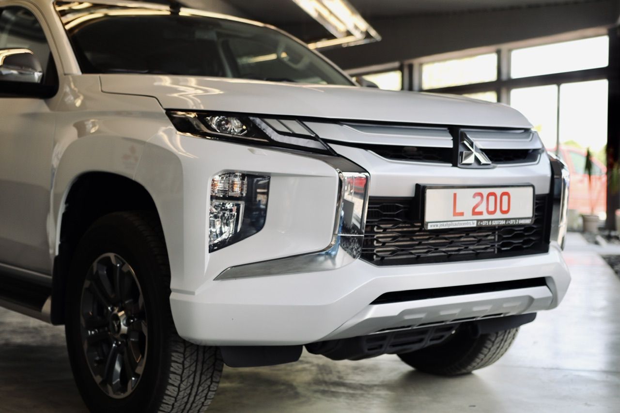 Balts mitsubishi tritons ir novietots izstāžu zālē.