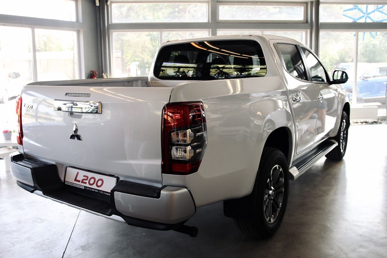 Balts mitsubishi triton pikaps ir novietots izstāžu zālē.