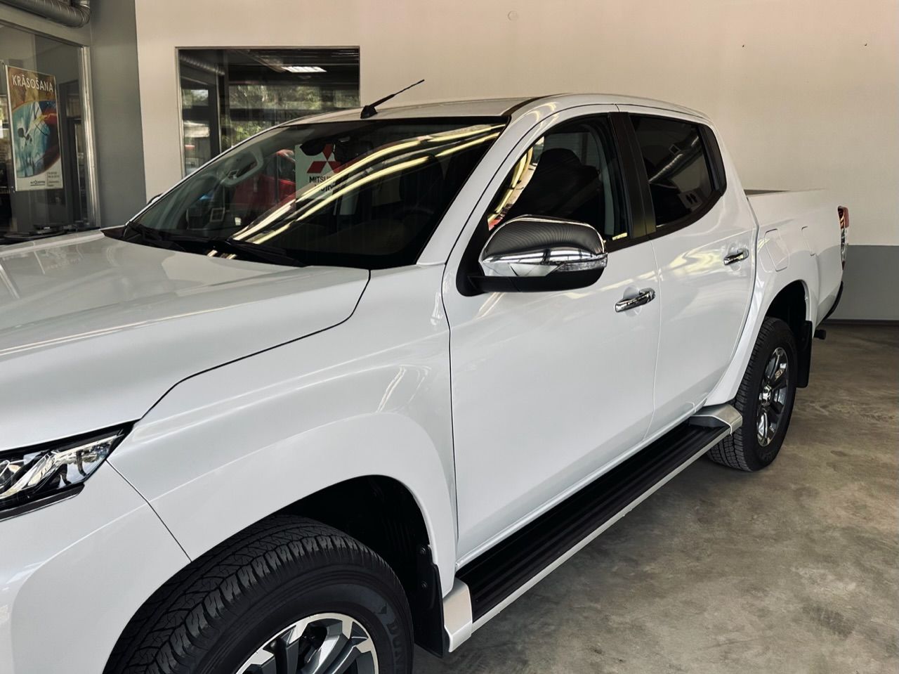 Balts pikaps stāv garāžā.