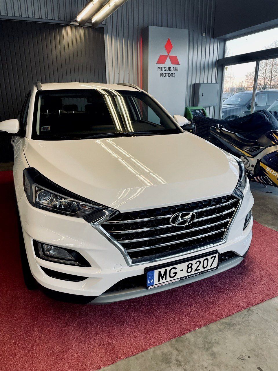 Balts hyundai tucson ir novietots izstāžu zālē.