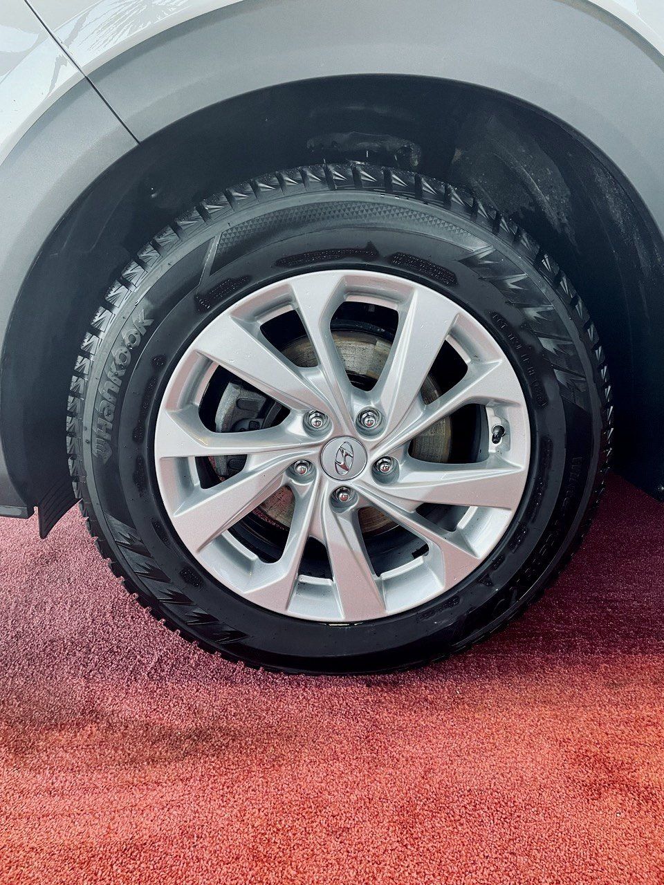 Tuvplāns no automašīnas riteņa uz sarkanā paklāja.