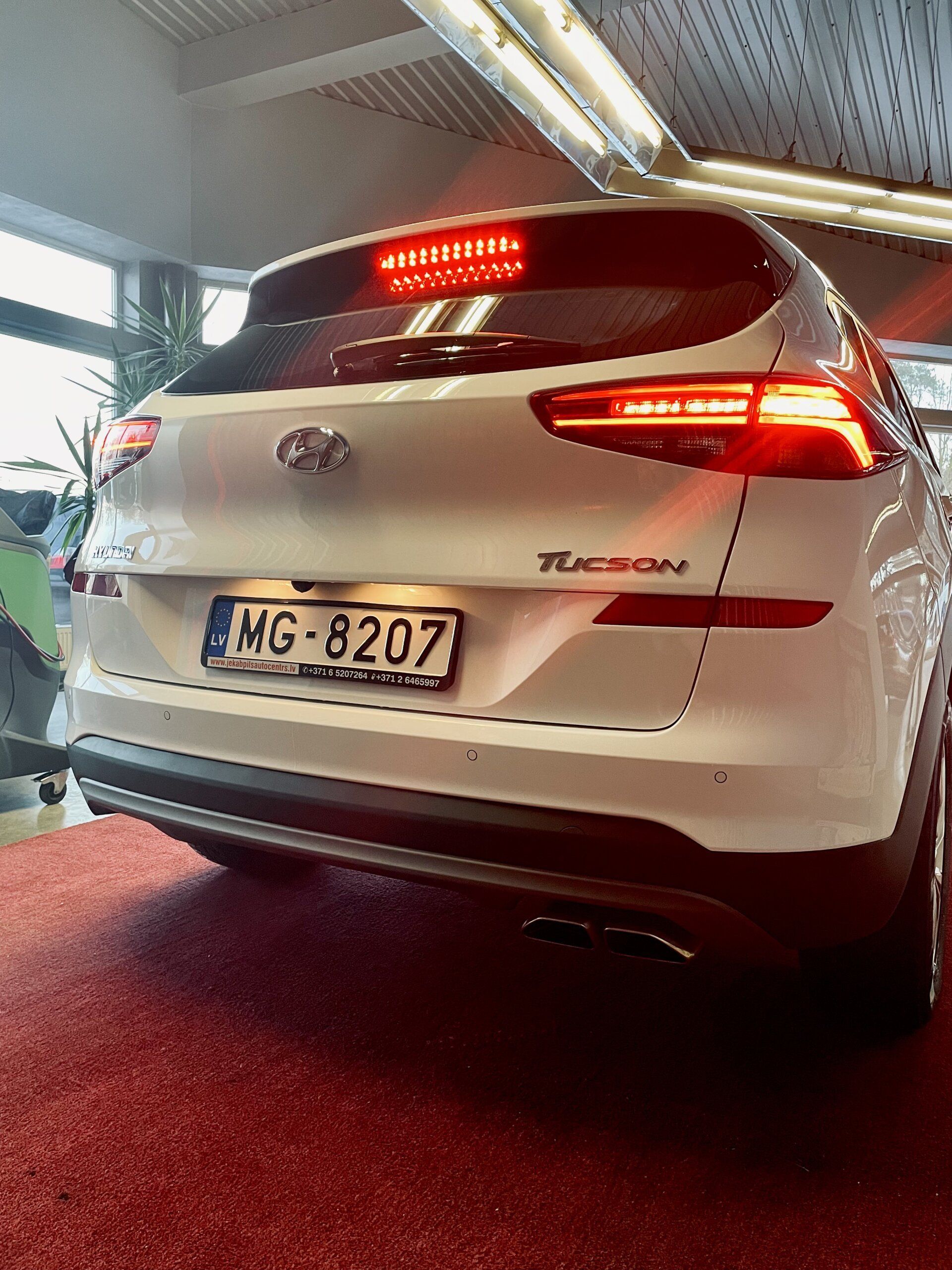 Balts hyundai tucson ir novietots izstāžu zālē.