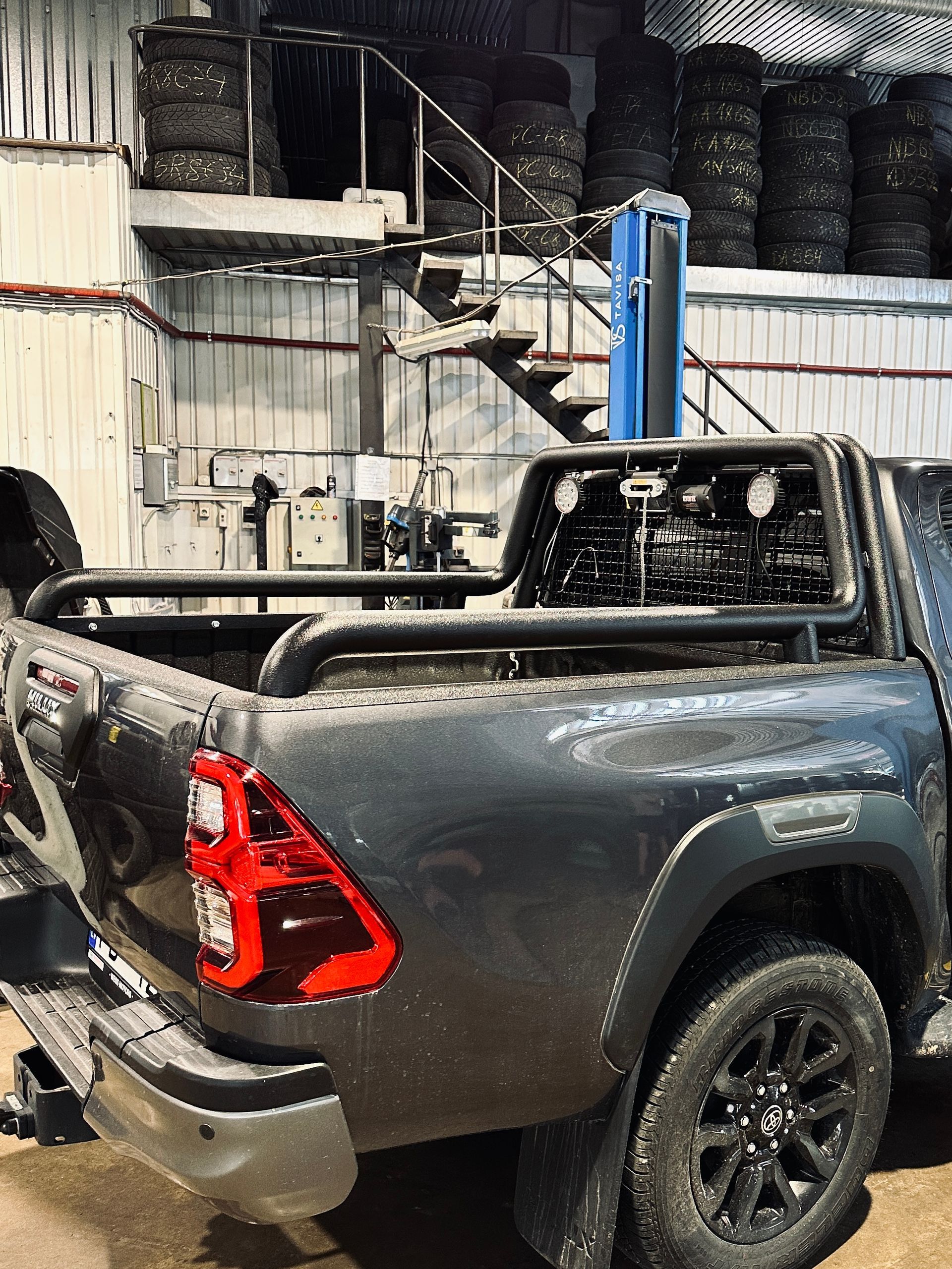 Riepu kaudzes priekšā stāv netīra kravas automašīna.