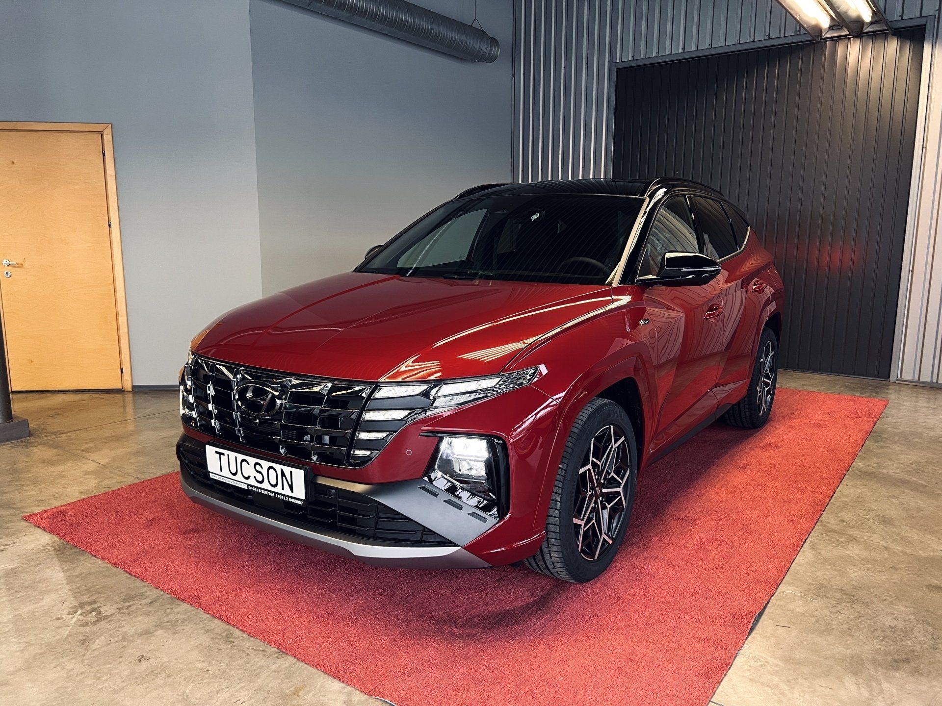 Sarkana mašīna ir novietota garāžā uz sarkana paklāja.