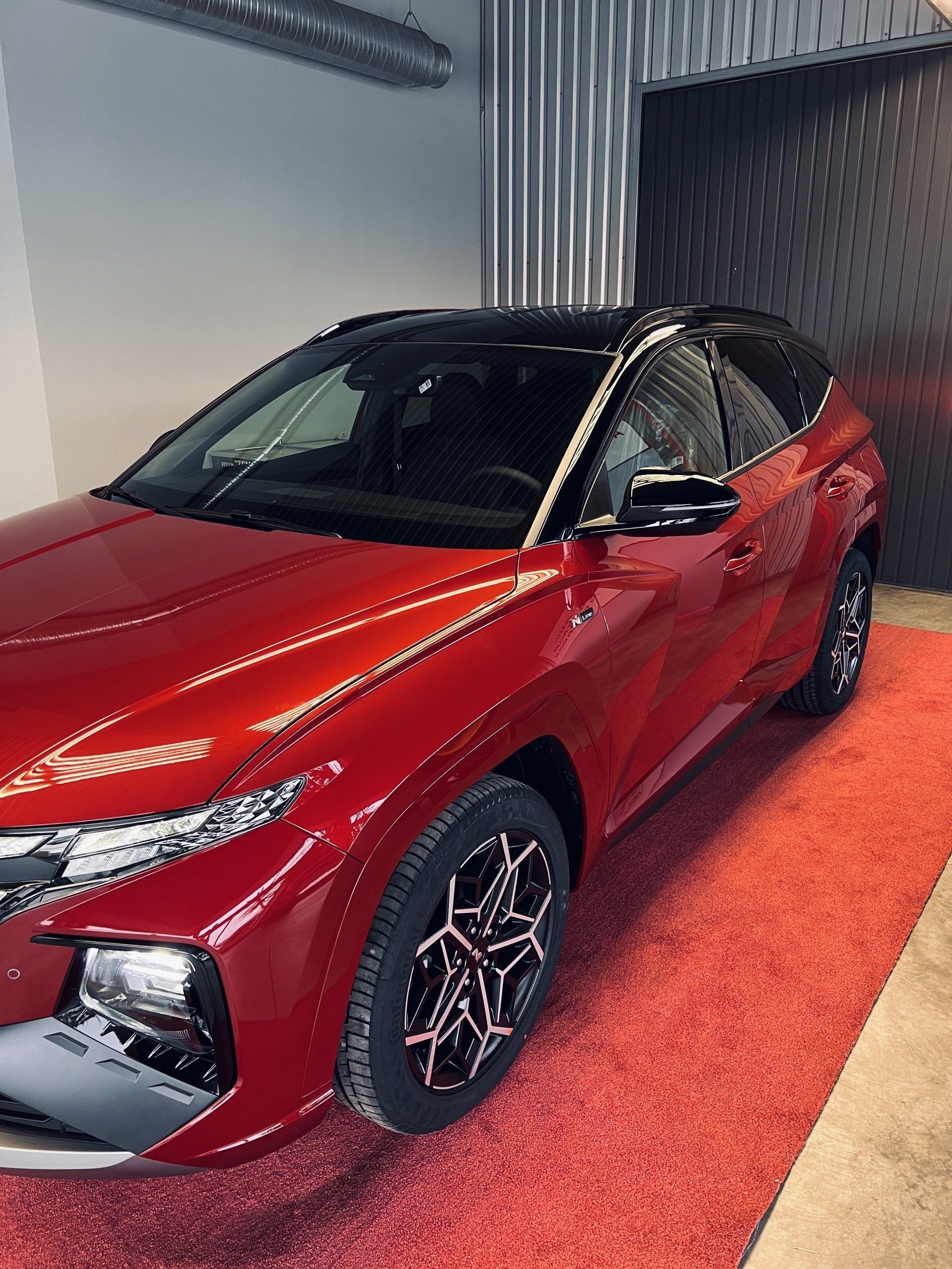 Sarkana mašīna ir novietota garāžā uz sarkana paklāja.