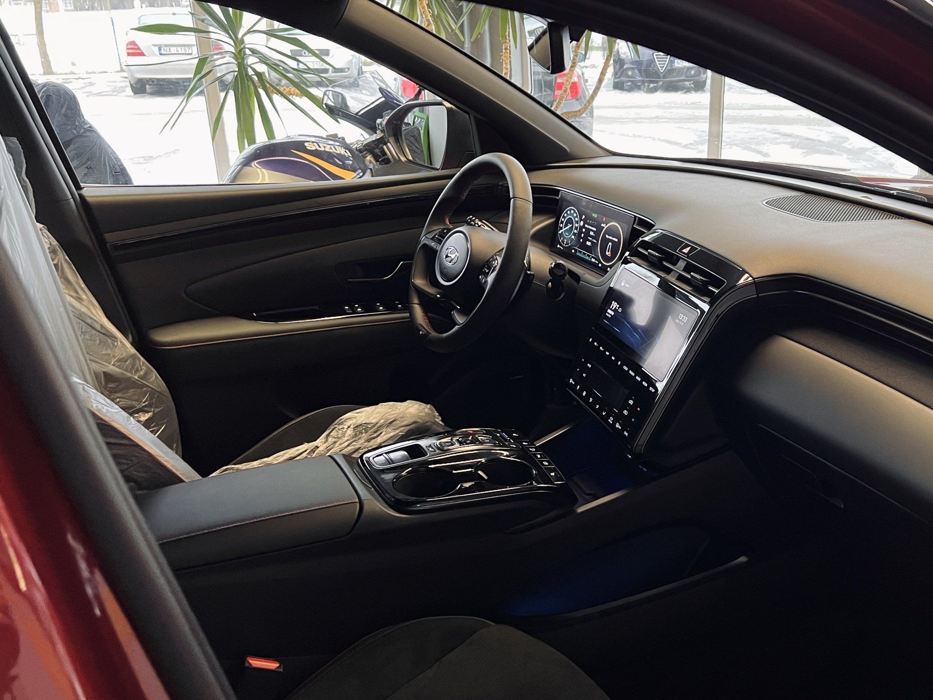 Sarkanas automašīnas salons ar stūri un instrumentu paneli.