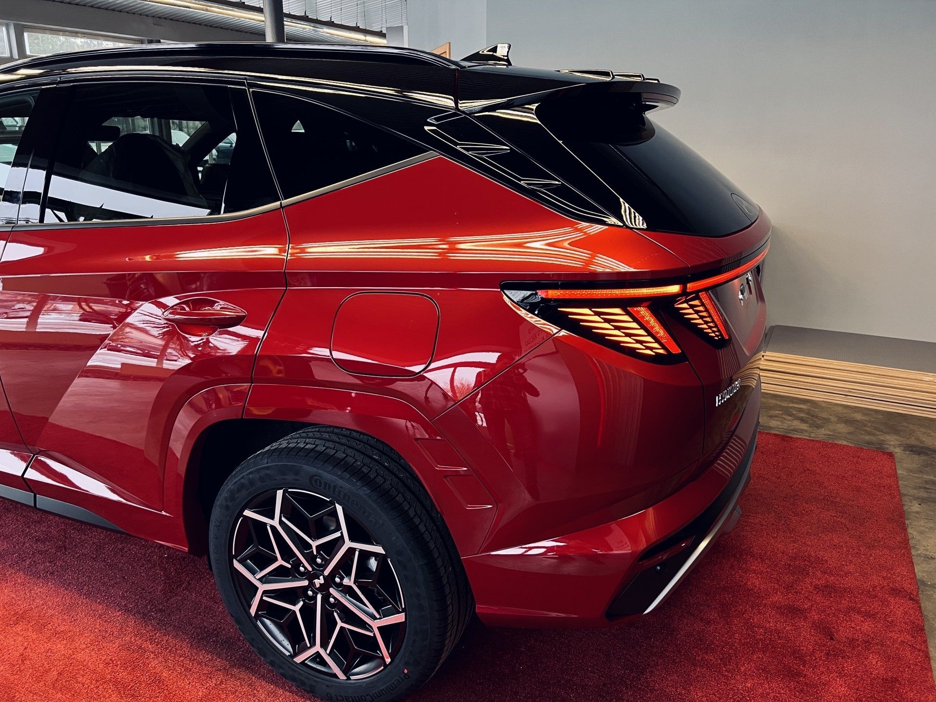 Sarkana automašīna ir novietota uz sarkana paklāja izstāžu zālē.