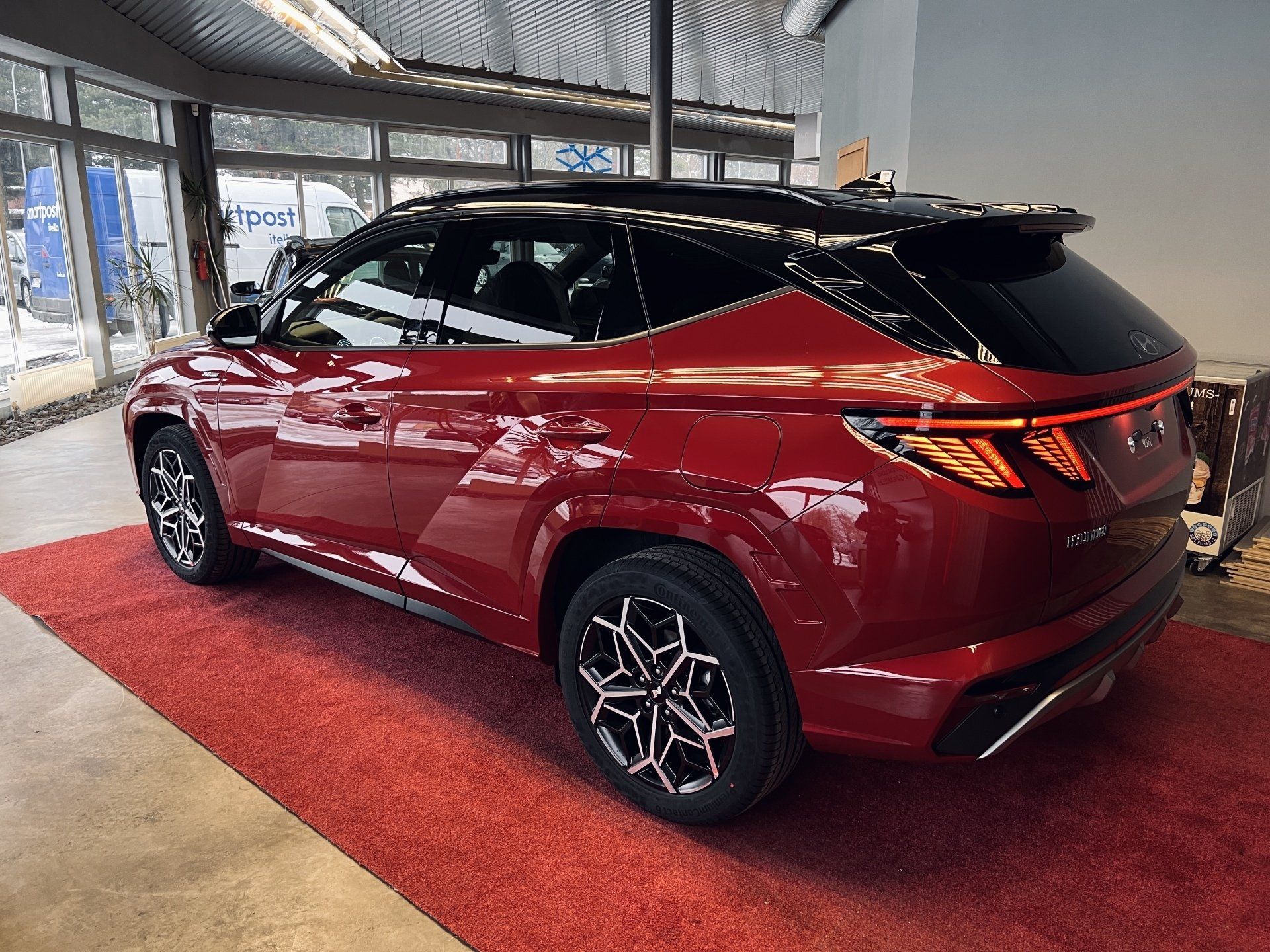 Sarkana mašīna sēž uz sarkanā paklāja izstāžu zālē.