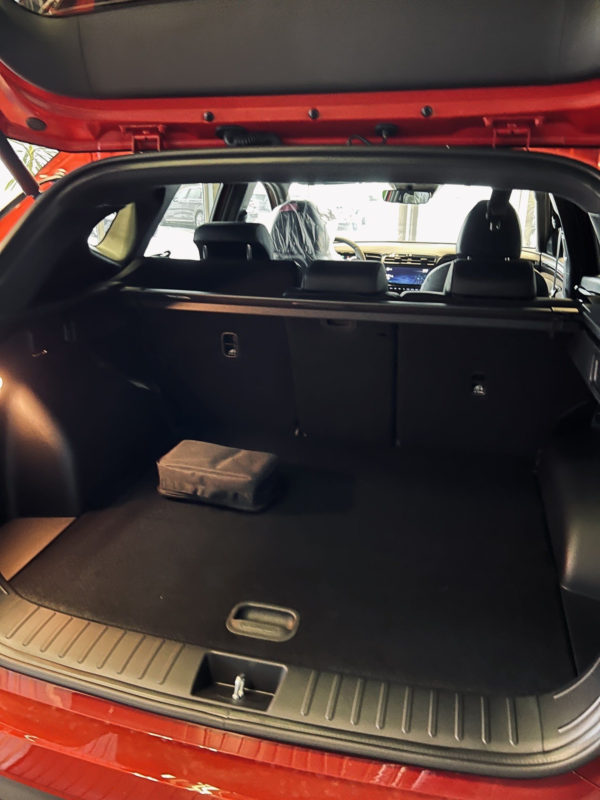 Sarkanas automašīnas aizmugure ar atvērtu bagāžnieku.