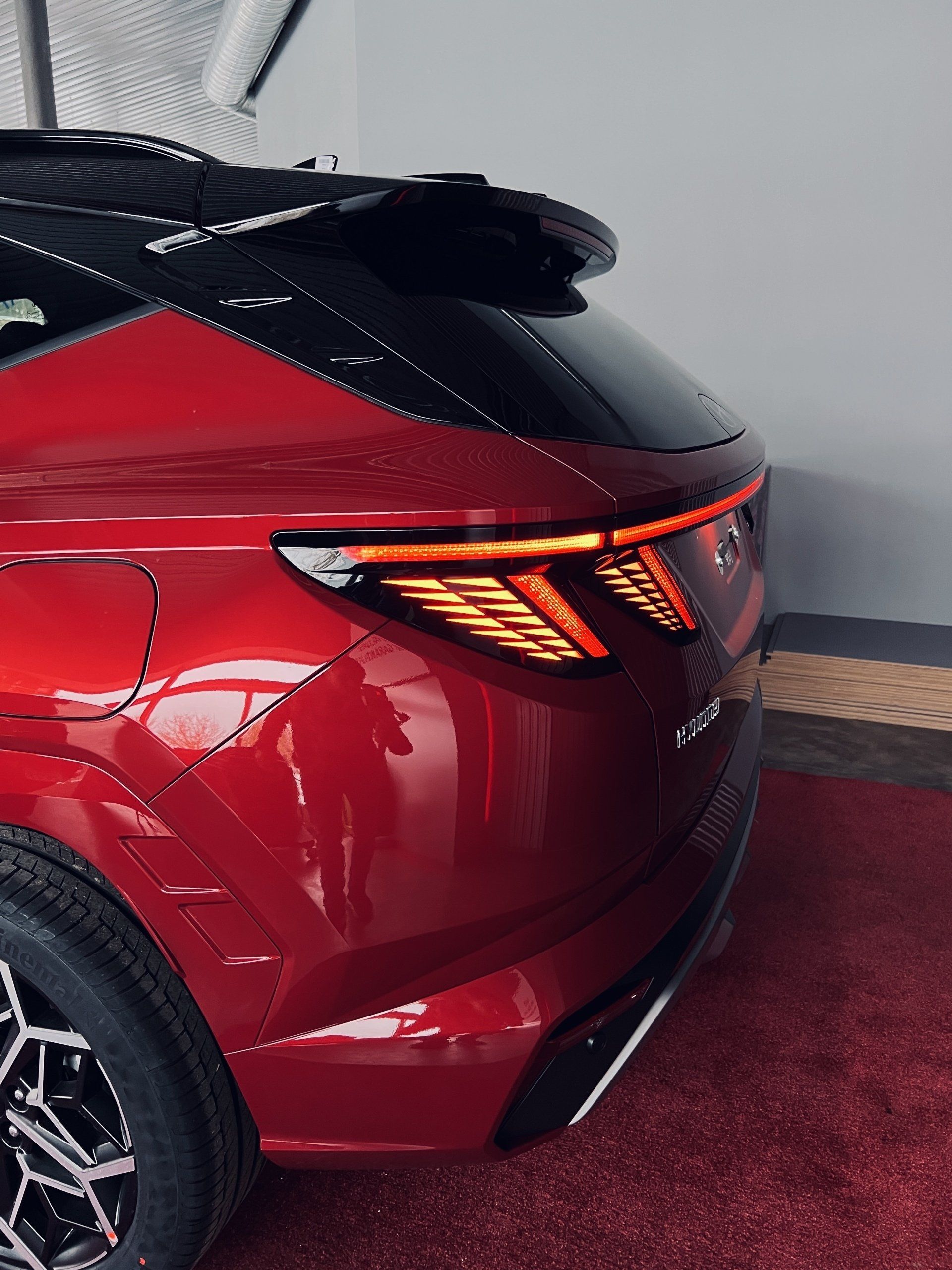 Sarkana mašīna stāv garāžā ar atvērtu bagāžnieku