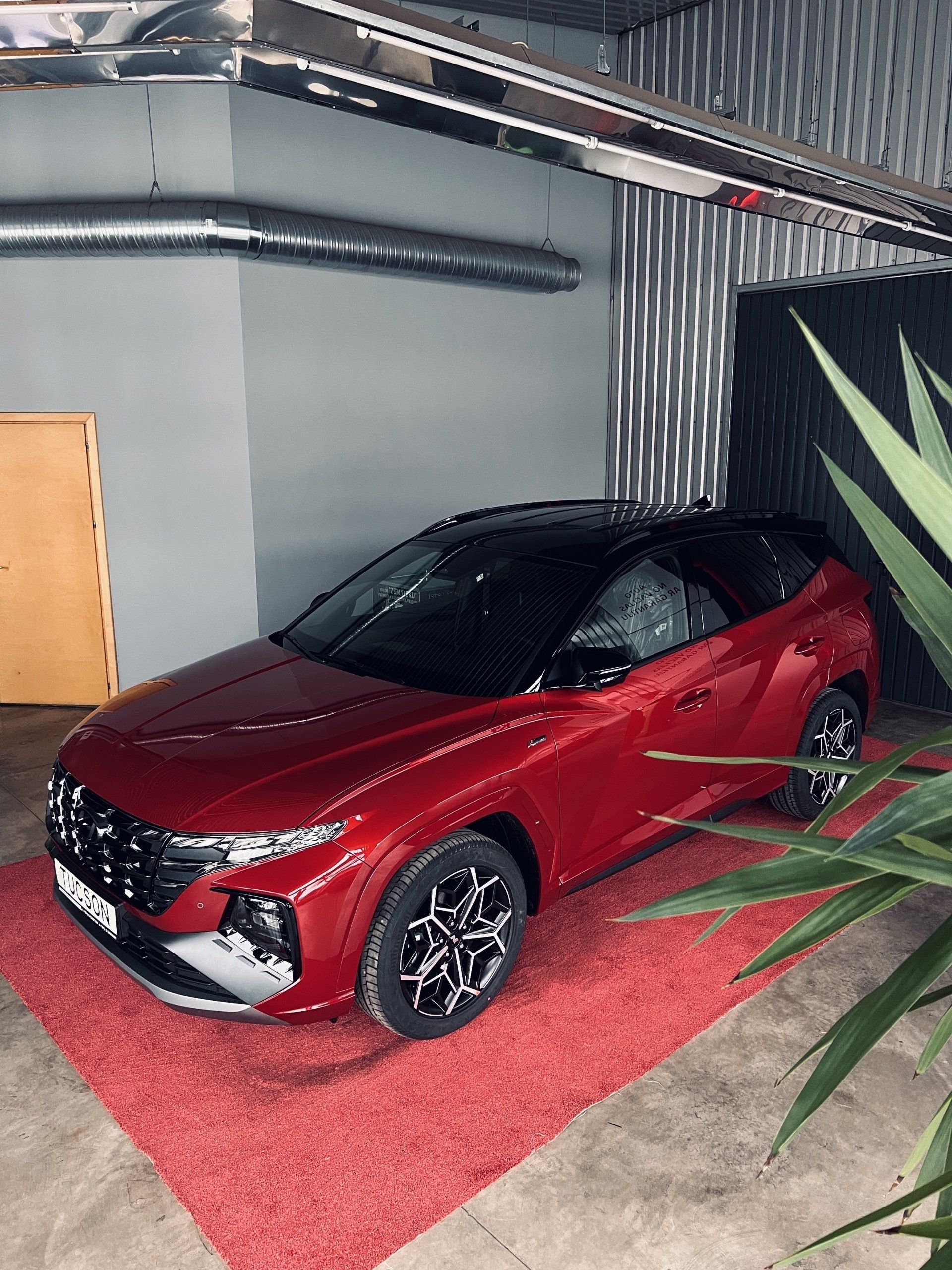 Sarkana mašīna stāv garāžā pie rūpnīcas.