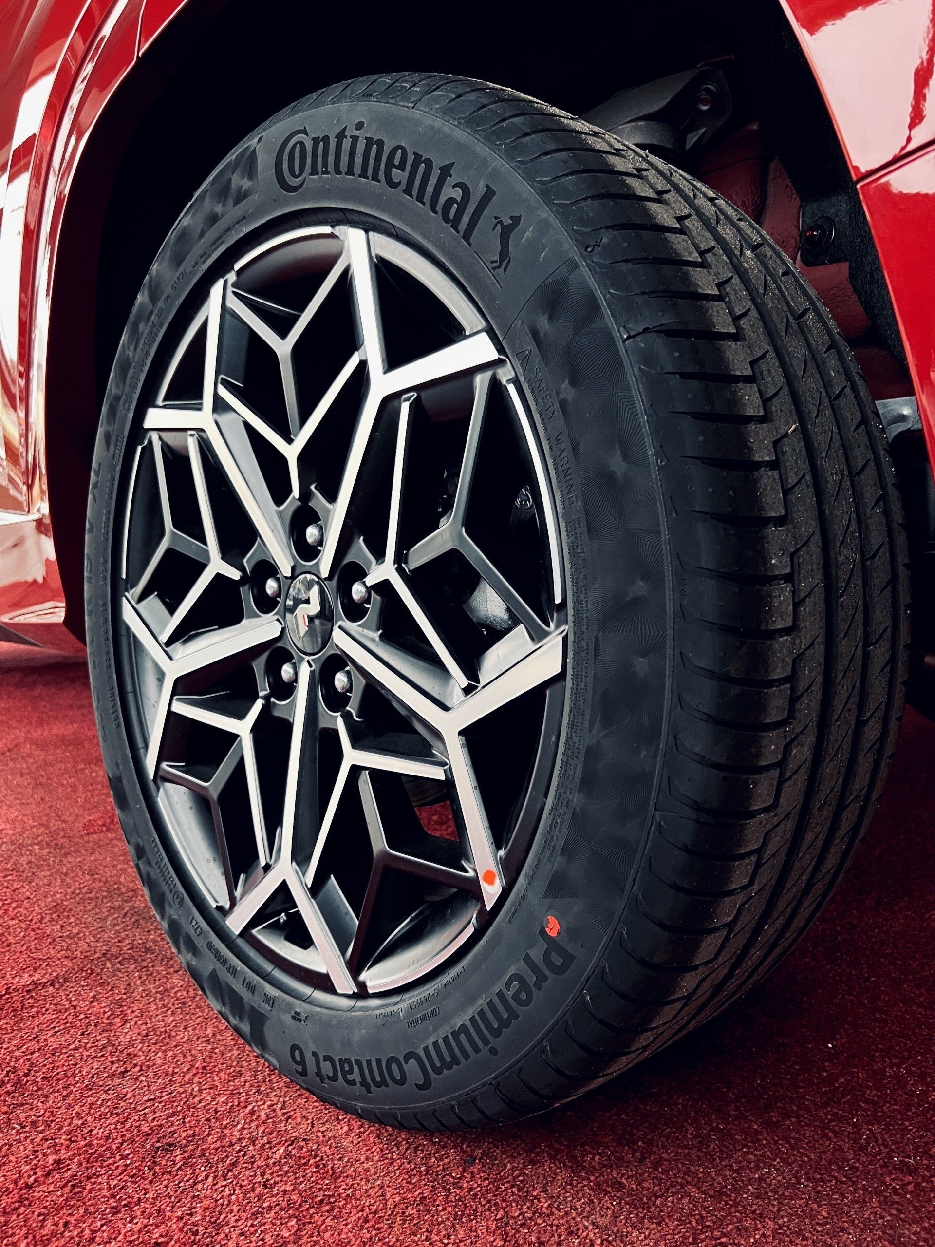 Kontinentālās riepas tuvplāns uz sarkanas automašīnas.