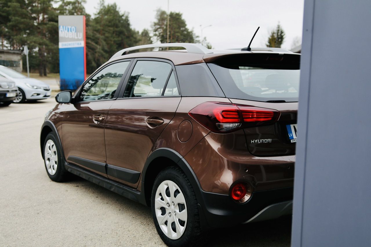 Brūna automašīna ir novietota stāvlaukumā pie ēkas.