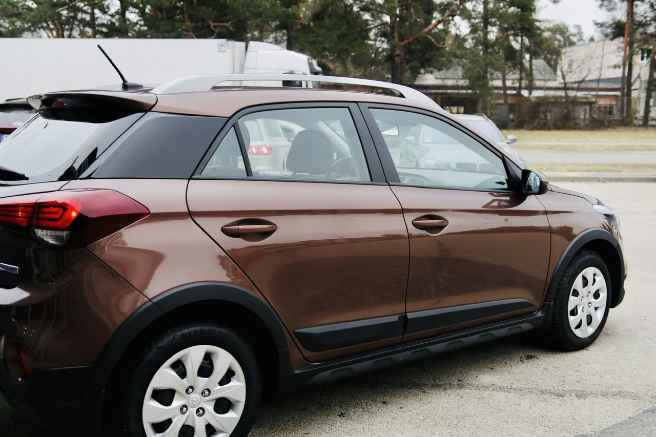 Ceļa malā stāv brūna mašīna.