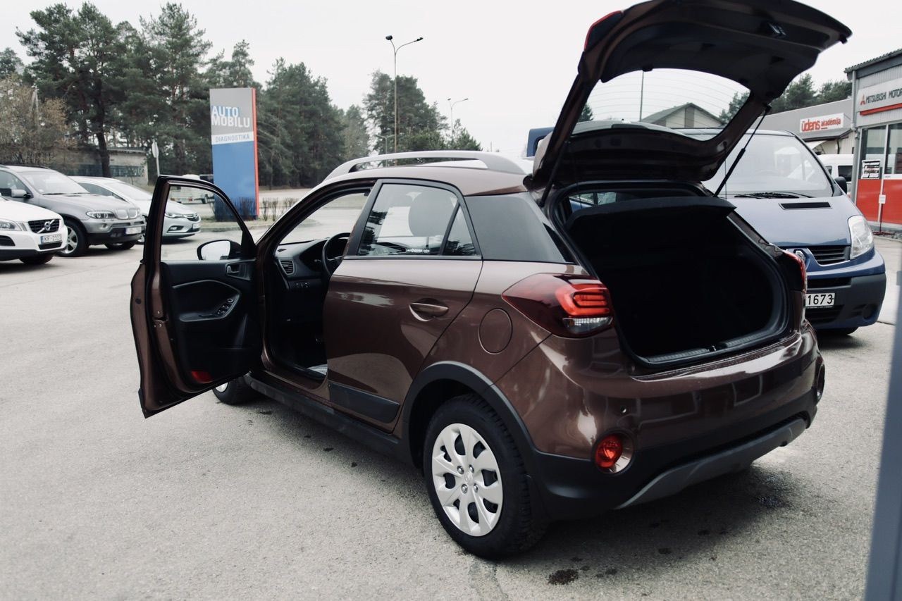 Stāvvietā stāv brūna automašīna ar atvērtu bagāžnieku