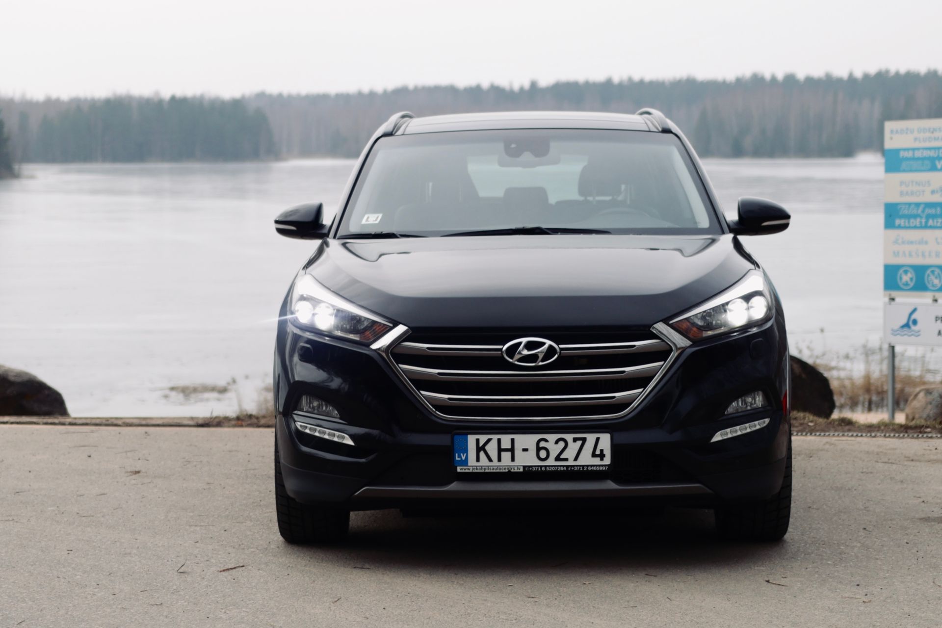 Ezera priekšā stāv melns hyundai tucson