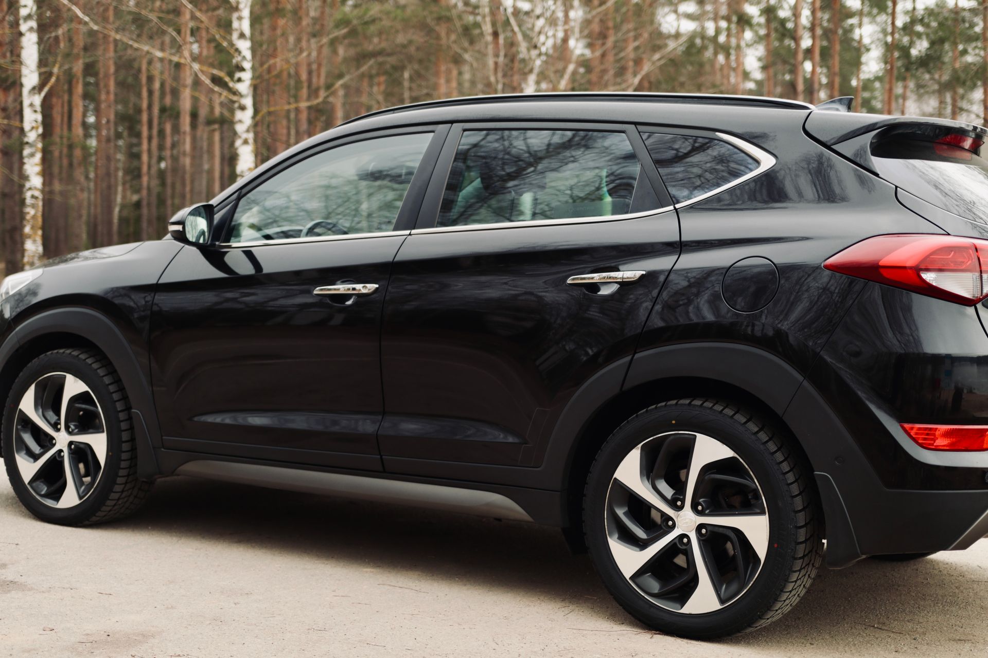 Meža priekšā stāv melns apvidus auto.