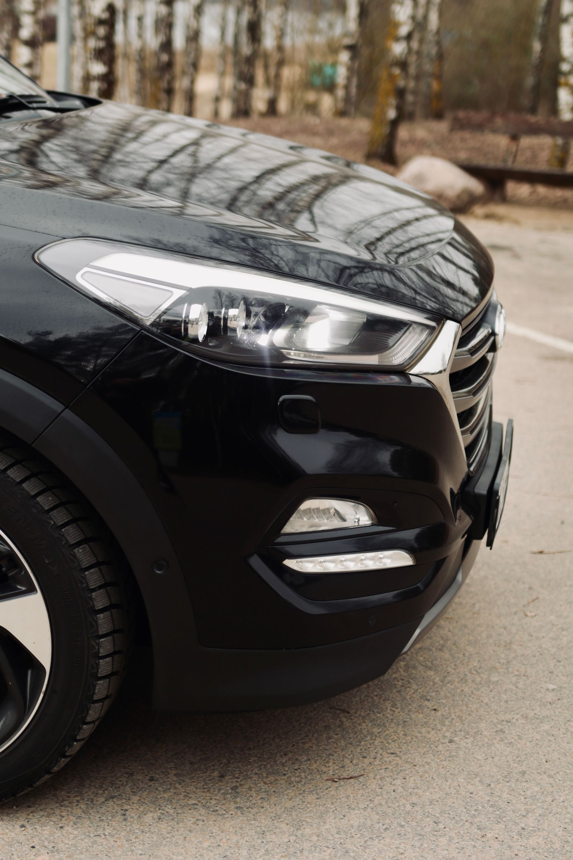 Stāvvietā stāv melna mašīna.