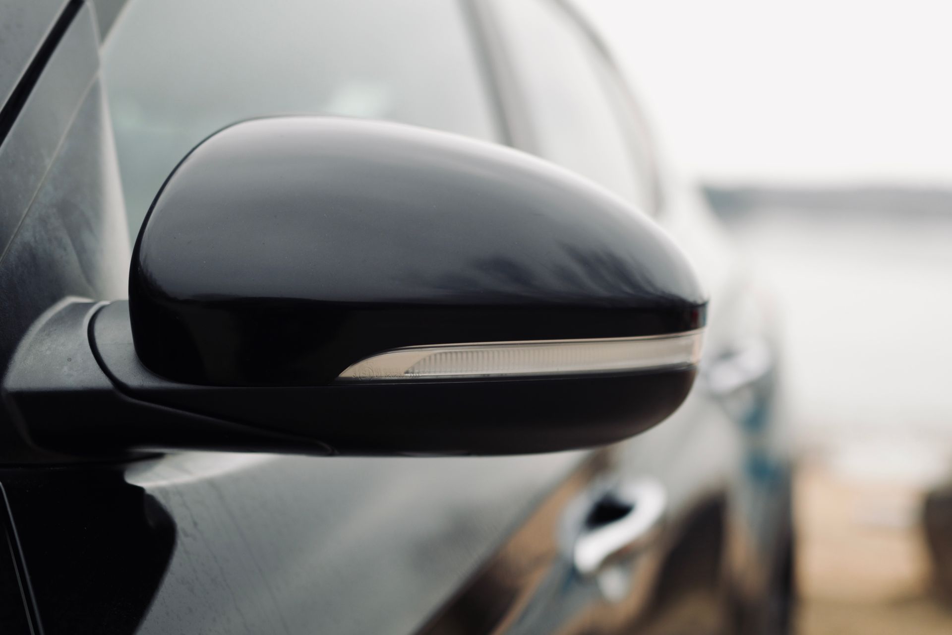 Sānskata spoguļa tuvplāns uz melnas automašīnas.