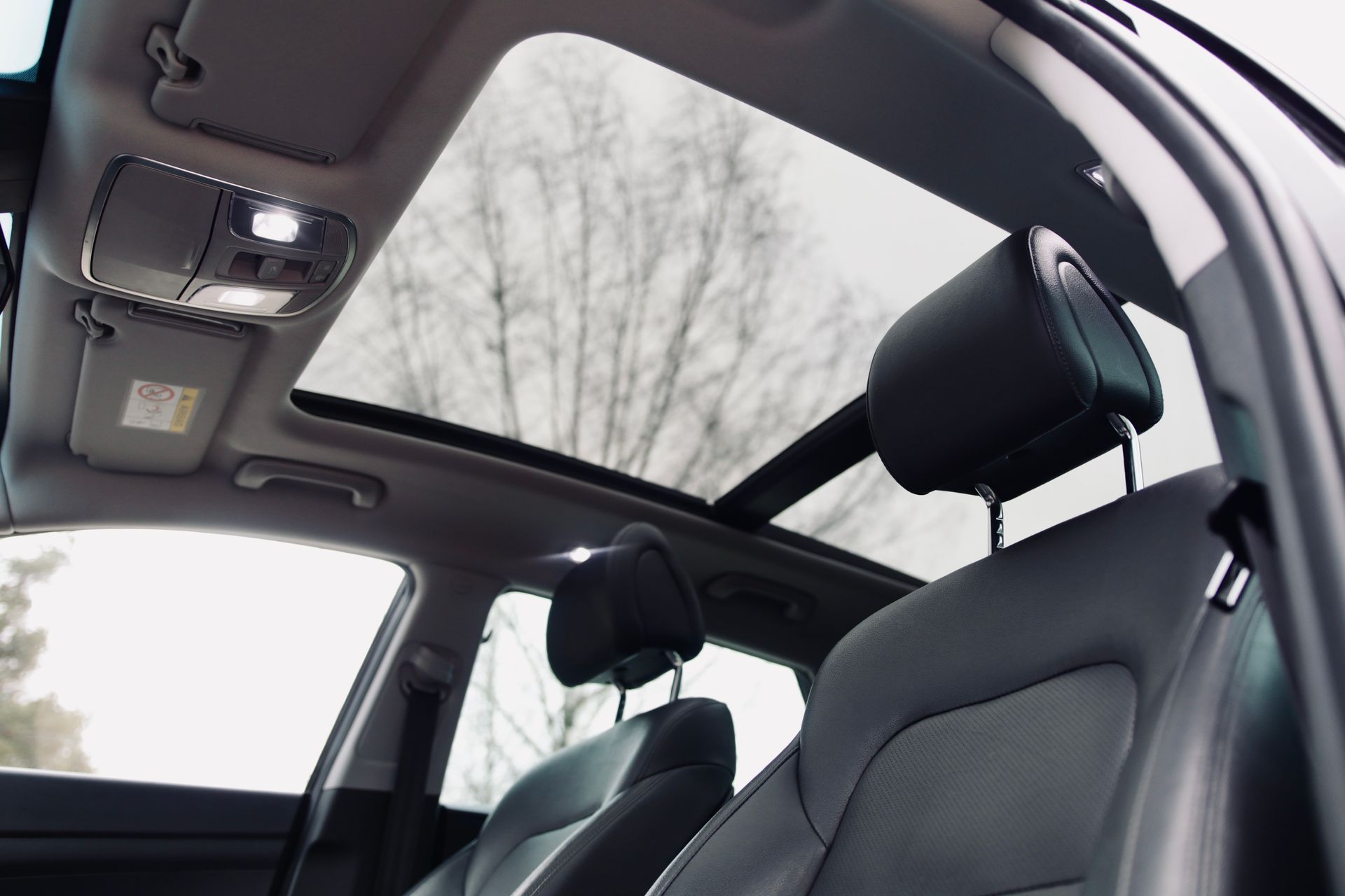 Automašīnas iekšpuse ar atvērtu jumta lūku.