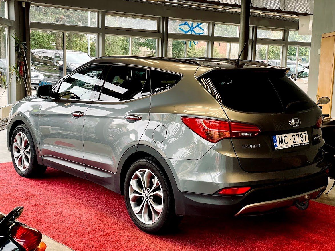 Pelēks apvidus auto ir novietots salonā pie motocikla.