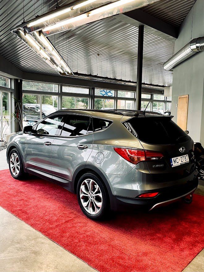 Pelēks apvidus auto ir novietots uz sarkana paklāja izstāžu zālē.