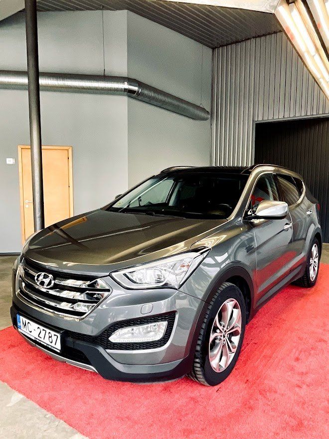 Pelēka automašīna ir novietota uz sarkanā paklāja salonā.