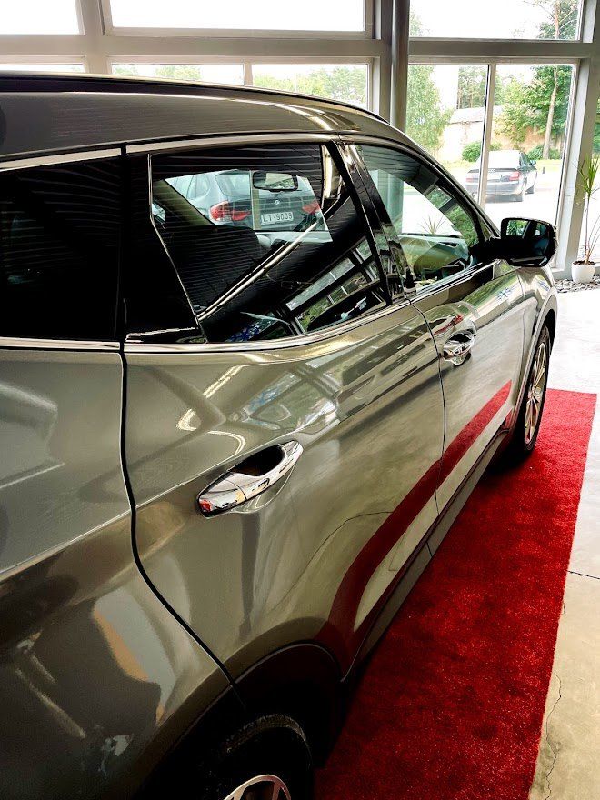 Automašīna ir novietota uz sarkanā paklāja salonā.