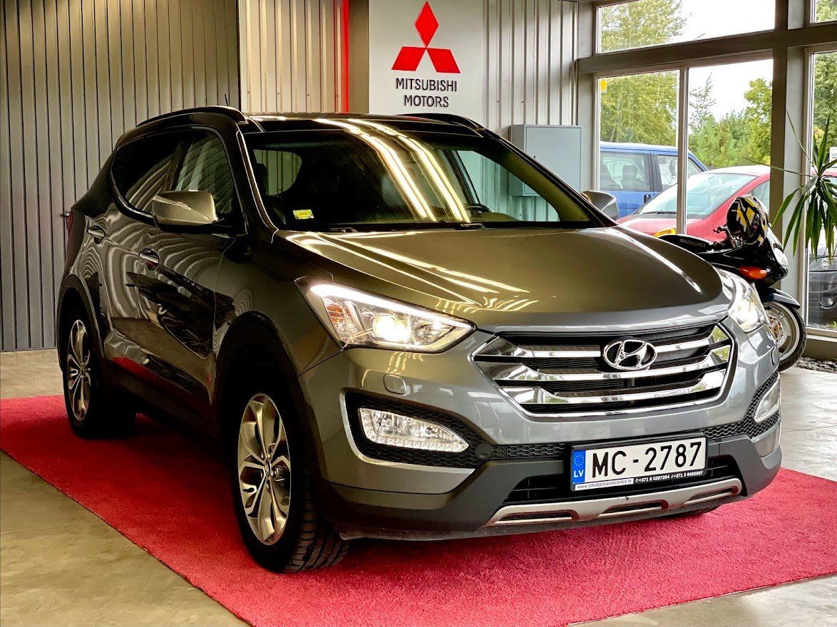Hyundai santa fe ir novietots izstāžu zālē pie mitsubishi zīmes.