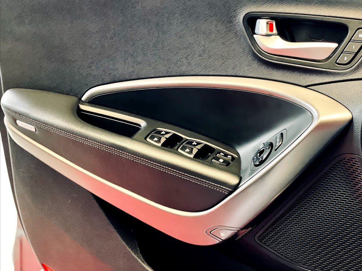 Tuvplāns ar automašīnas durvju rokturi uz sarkanas automašīnas